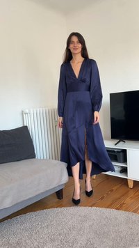 Tamsiai mėlyna satino suknelė su giliais V formos iškirpte ir ilgomis rankovėmis. Suknelė turi priekį skeltą, plačią apačią ir aptemptą viršutinę dalį, derinama su juodais aukštakulniais.