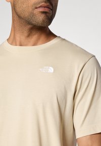 Μπεζ βαμβακερό t-shirt με στρογγυλή λαιμόκοψη, κοντά μανίκια και λευκό κεντητό λογότυπο στο αριστερό στήθος. Λείο ύφα σμα και άνετη εφαρμογή.