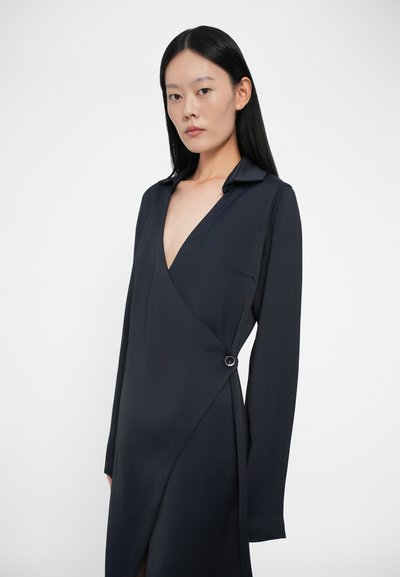 Rochie în stil navy, cu mâneci lungi și decolteu adânc în V, având un detaliu cu nasture la talie și o textură elegantă, netedă.