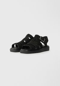 Sandalias de ante negro con diseño de punta abierta, que cuentan con múltiples tiras en la parte superior, un broche para ajuste y una suela de goma texturizada.