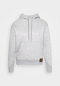 Sudadera gris hecha de una tela suave, con un bolsillo frontal, capucha ajustable y un pequeño parche con el logo en el dobladillo. Diseño clásico de tipo pullover.