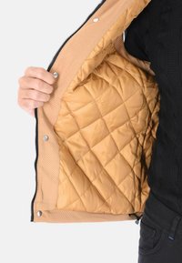 Giubbotto trapuntato color beige con cerniera nera, che mostra un rivestimento interno liscio e lucido. L'interno presenta un motivo a rombi e bottoni a pressione.