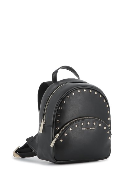 Svart Michael Kors läderryggsäck med silverfärgade nitar, framficka med dragkedja, handtag på toppen och justerbara axelremmar mot en vit bakgrund.