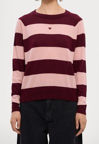Pull en tricot rayé bordeaux et rose avec un col rond, présentant un petit détail en forme de cœur sur la poitrine ainsi que des poignets et un ourlet côtelés.