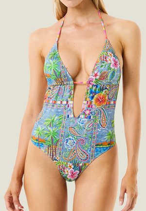 Donna che indossa un costume da bagno colorato a fantasia tropicale, con collo all'americana, scollo profondo a V e motivi floreali e di palme.