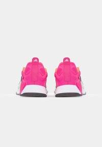 Sneakers con tomaia in rete, predominantemente bianchi, con accentuazioni rosa sul tallone e dettagli neri. Suole in gomma textured e etichette con logo visibili.