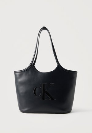 Borsa tote in pelle nera con manici lunghi doppi e logo CK impresso in rilievo sul davanti, su sfondo semplice.