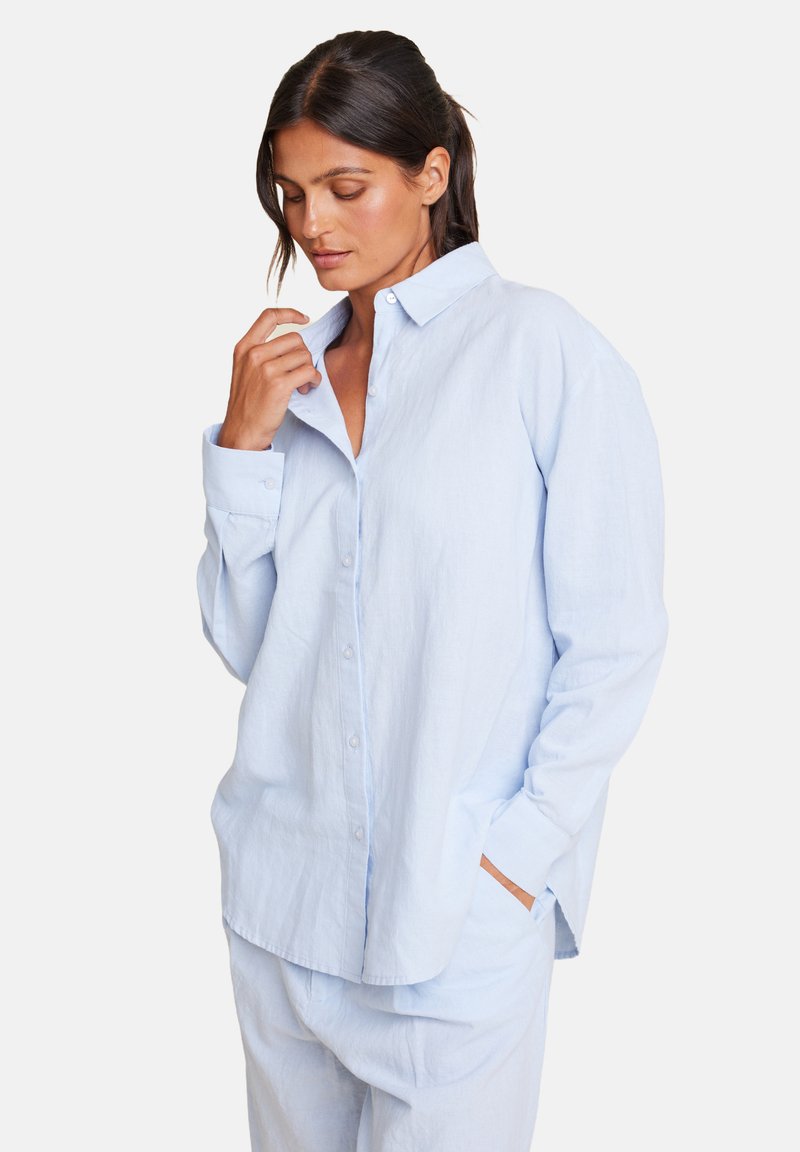 Lyseblå lin skjorte med en avslappet passform, knappes front og krage. Lange ermer har knappede mansjetter. Merkbar fickdetalj med aksent.
