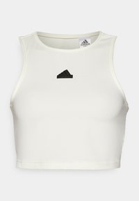 Fehér, rövidített sport felső sima anyagból, kerek nyakkivágással és egy kis fekete Adidas logóval az elején.