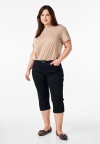 T-shirt beige a maniche corte, pantaloni neri a vita alta con tasche laterali e ballerine con stampa leopardata e dettaglio fiocco. Linee pulite e design semplice.
