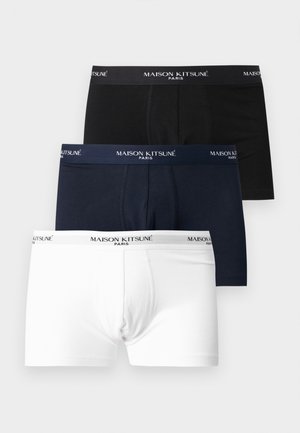 Trois boxers pour homme pliés, en noir, bleu marine et blanc, avec des ceintures élastiques de marque indiquant "MAISON KITSUNÉ PARIS."