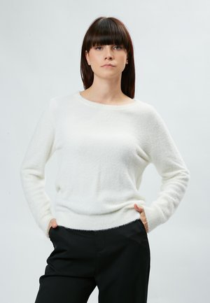 Un pull blanc et duveteux avec un col rond et des manches longues, associé à un pantalon noir. Le vêtement a une texture douce et une coupe décontractée.
