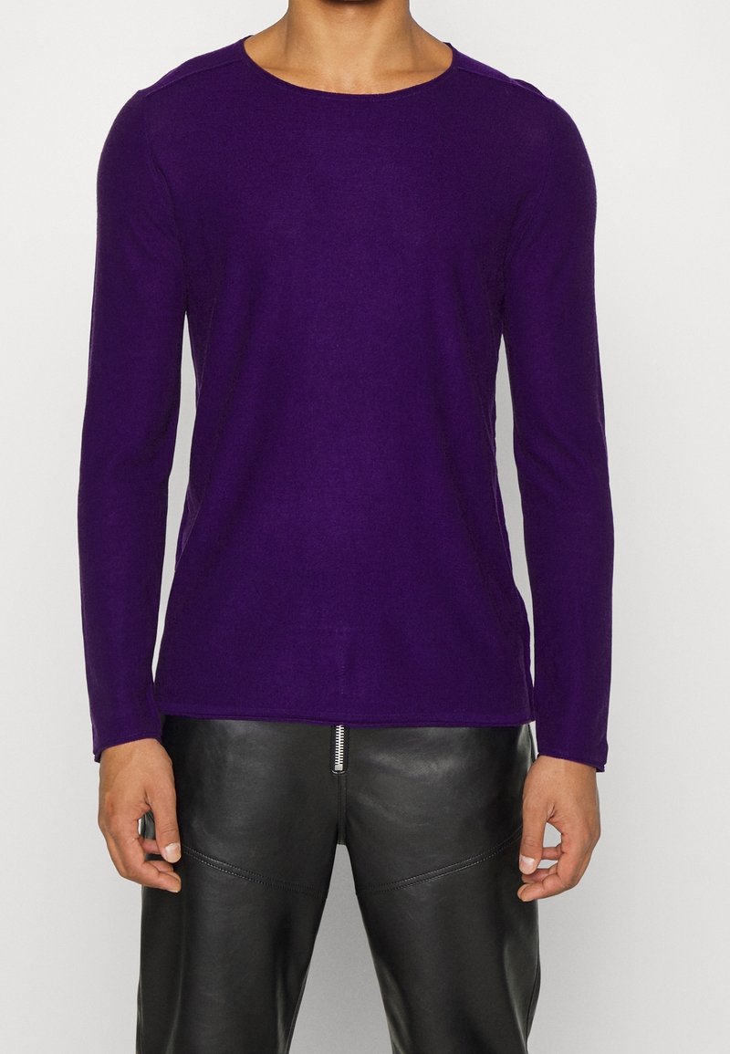 Lila långärmad skjorta i mjukt material med rundad halsringning, med sidosprund och sydda axeldetaljer. Bärs med svarta läderbyxor.