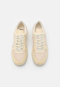 Sneakers basse in beige e crema. Realizzati in rete e pelle con una finitura testurizzata. Presentano lacci bianchi e un design a punta rotonda.