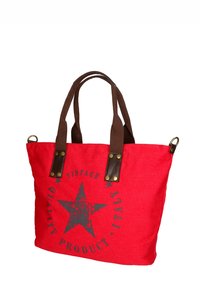 Borsa tote in tela rossa con manici in tessuto marrone, caratterizzata da una grafica a stella e un design testuale. Include dettagli in ottone per maggiore durata.