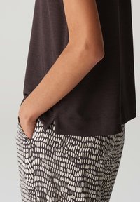 Donkerbruin, kort mouwtopje gecombineerd met een zwart-wit gestreepte broek. De broek heeft een gladde textuur en een aansluitend ontwerp.