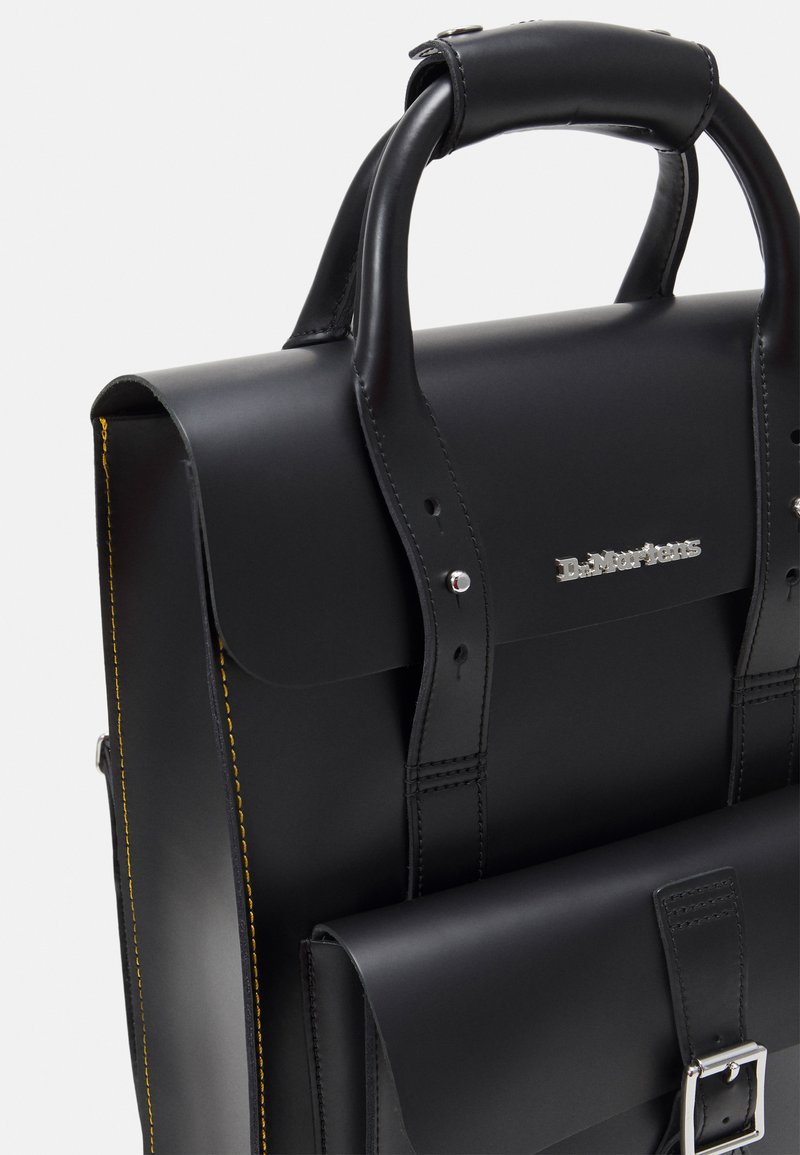 Sort læder dokumentmappe med et struktureret design, der har gule stikninger, sølvfarvet hardware og en frontlomme med en spænde-lukning.