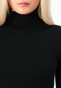 Μαύρο ριγέ πουλόβερ τύπου τζάκετ φτιαγμέν�ο από πλεκτό ύφασμα, με ψηλό γιακά και εφαρμοστή σιλουέτα. Λείος υφασμάτινος σχεδιασμός με κατακόρυφες γραμμές.