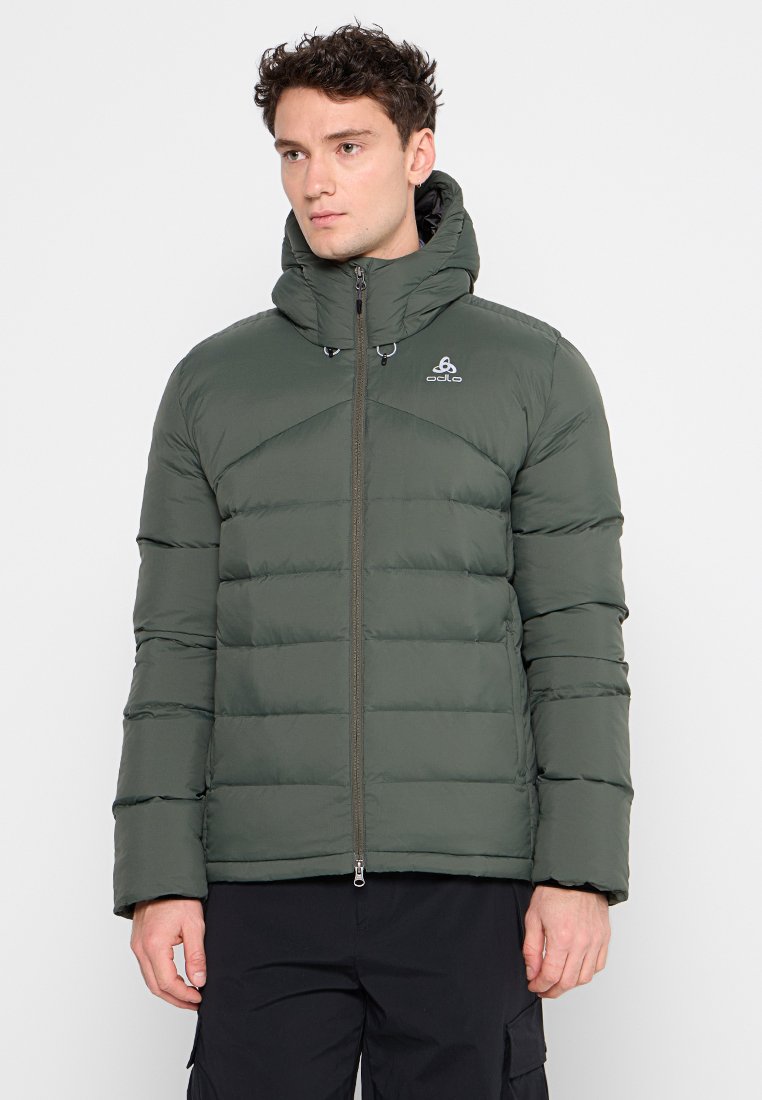 Giacca imbottita verde con chiusura a zip frontale, cappuccio regolabile e dettaglio del logo. Presenta un design a righe orizzontali e polsini elasticizzati per garantire calore.