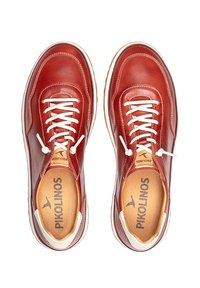 Zapatillas de cuero rojo con cordones blancos, punteras redondeadas y un interior acolchado. Marca visible en las plantillas. Textura suave con costuras sutiles.