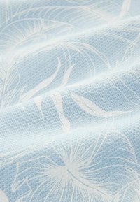 Țesătură de culoare albastru deschis, cu un model texturat, prezentând contururi florale albe. Designul afișează o țesătură moale și complexă.