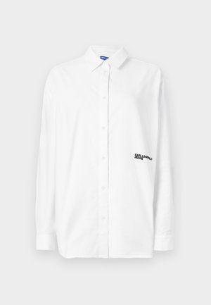 Camisa blanca de botones con mangas largas, de material de algodón, con un cuello clásico y logo de la marca bordado en el lado izquierdo del pecho.