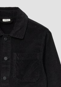 Schwarze Cordjacke mit knöpfbarem Vorderteil, Kragen, einer Brusttasche und gerippter Textur. Labels sind im Kragen sichtbar.