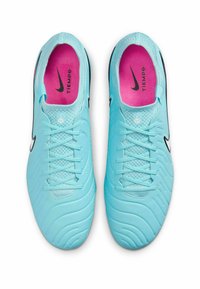 Bottes de football bleu clair avec une tige en synthétique texturé, un swoosh Nike noir, une semelle intérieure rose et un système de laçage traditionnel.