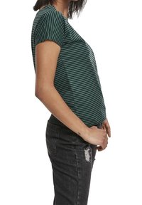 Zelené pruhované tričko s krátkým rukávem, fitted střih a jemným nárůstem na rameni, v kombinaci s roztrhanými černými skinny džíny.