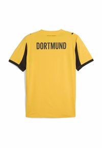 Geltonas sportinis marškinėlis su juodomis rankovėmis, ant nugaros yra užrašas "DORTMUND" storomis juodomis raidėmis. Slydus audinys su nežymia tekstūra.