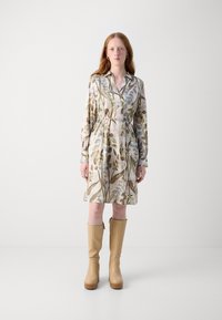 Rochie cu imprimeu floral dintr-un material ușor, cu guler, mânecă lungă și centură în talie. Asortată cu botine bej cu toc înalt, până la genunchi.