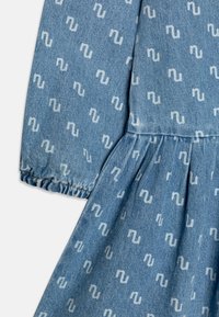 Denimkjole med et lyseblått stoff som har et gjentatt hvitt bølgemønster, rynket midje og elastiske mansjetter på lange ermer.