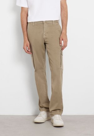 Beige cargo pants with two side pockets, a straight fit, and a durable fabric. Paired with white sneakers and a plain white t-shirt.