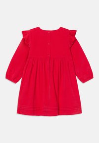Rochie roșie cu mâneci lungi, din material texturat, cu umăr volanat, închidere cu nasturi la spate și talie strânsă cu pliseuri decorative.