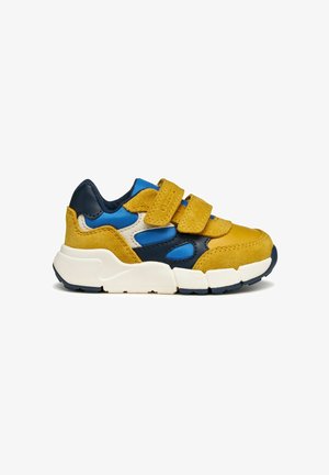 Zapatilla multicolor que presenta gamuza amarilla, cuero azul marino y tela azul. Dos correas de velcro en la parte superior, suela blanca gruesa.