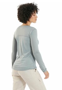 Lichtgrijs langemouwen shirt met een textuurdesign, voorzien van een gladde rugpaneel en een ronde halslijn. De stof lijkt rekbaar en comfortabel.