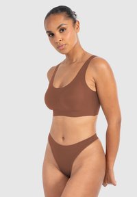 Bruine naadloze bh en bijpassende hoge slip, gemaakt van zacht materiaal met brede banden en een minimalistisch ontwerp. Gladde textuur, zonder patronen.