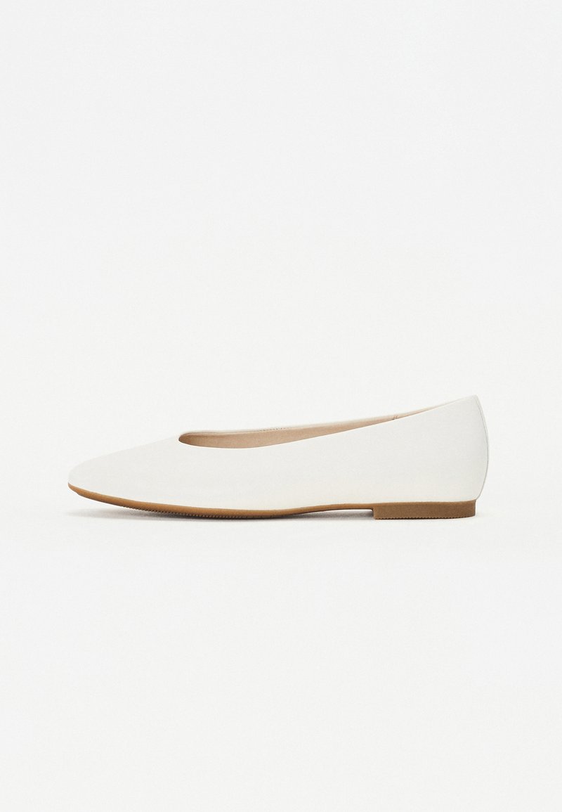 Chaussure plate blanche avec un bout rond, texture en cuir lisse, design minimaliste et fine semelle en caoutchouc brun.
