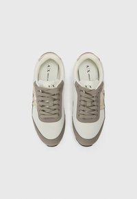 Scarpe sportive grigie e bianco sporco con tomaia in mesh, dettagli in suede testurizzato e lacci piatti. Presentano solette con marchio e colletto imbottito.
