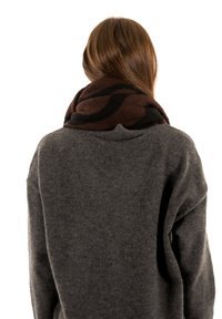 Écharpe à motifs marron et noir enroulée autour du cou, fabriquée en tissu doux et texturé ; portée avec un pull gris.