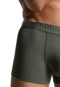 Dunkelgrüne Boxershorts mit strukturiertem Finish, ausgestattet mit einem Bund, der mit "PUMA" in kontrastierender Farbe geprägt ist.
