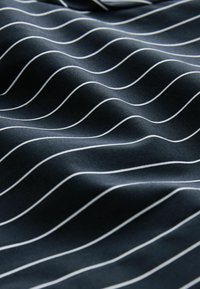 Navy fabric with white wavy stripes, displaying a smooth texture. The design creates a dynamic visual effect across the surface.