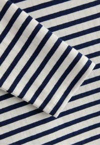 Marinblått och vitt randigt tyg med horisontella linjer på en räfflad textur, med en vikt ärm som tydligt visar mönstret.