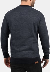 Marine blauwe crewneck sweatshirt met een textuurgebreide stof, ribgebreide mouwen en zoom, met een klein leren logo-op-patch rechtsonder.