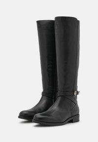 Stivali alti neri in pelle, con una texture liscia, cerniera laterale e un accento decorativo dorato sulla cinghia. Punta quadrata e tacco basso.