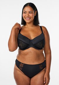 Czarny biustonosz z koronkowymi zdobieniami, gładkimi satynowymi miseczkami i regulowanymi ramiączkami. Pasujące czarne majtki z koronkowymi akcentami po bokach.