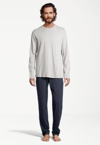 Grijze lange mouw shirt met een ronde hals, gecombineerd met donkerblauwe loungebroeken, met een relaxed fit en zachte textuur.
