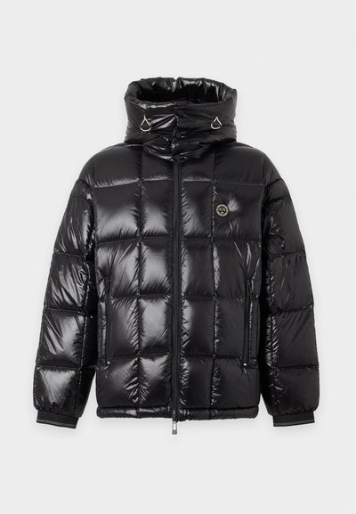 Veste matelassée noire brillante avec col montant, fermeture éclair complète à l'avant, poches latérales zippées et petit badge rond avec logo sur la poitrine.