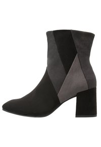 Stiefelette mit Blockabsatz, hergestellt aus schwarzem und grauem Wildleder mit geometrischem Farbblock. Die Zehenpartie ist spitz und glatt.