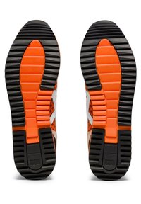 Semelle extérieure de chaussure en caoutchouc noir avec des rainures profondes, des accents orange et un motif texturé. Marque notable visible sur le talon.